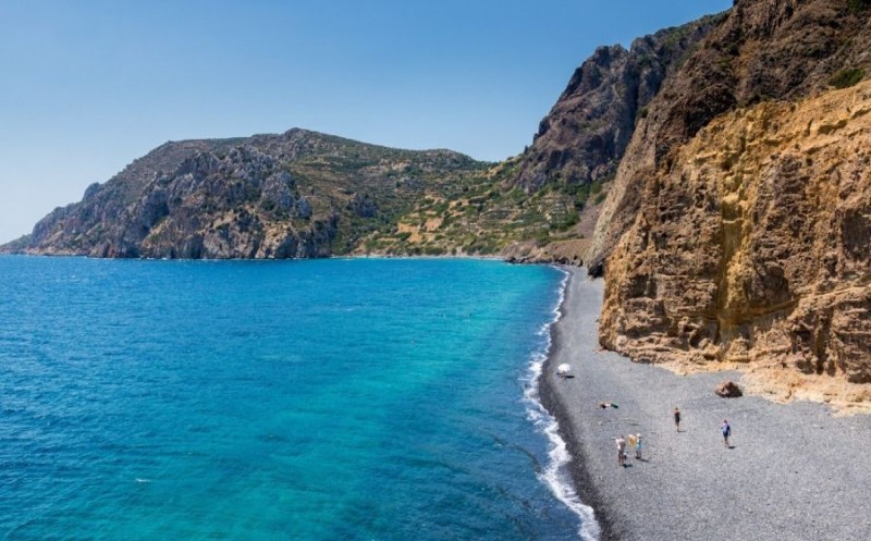 Ζαφειρένια νερά και μαύρα βότσαλα: Η εξωπραγματική παραλία ελληνικού νησιού με την χρωματική αντίθεση που ξεχωρίζει
